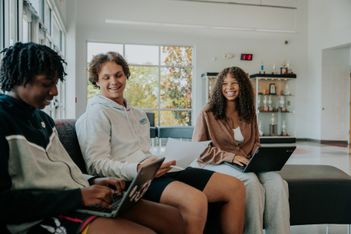 a group of people sitting on a couch with laptops